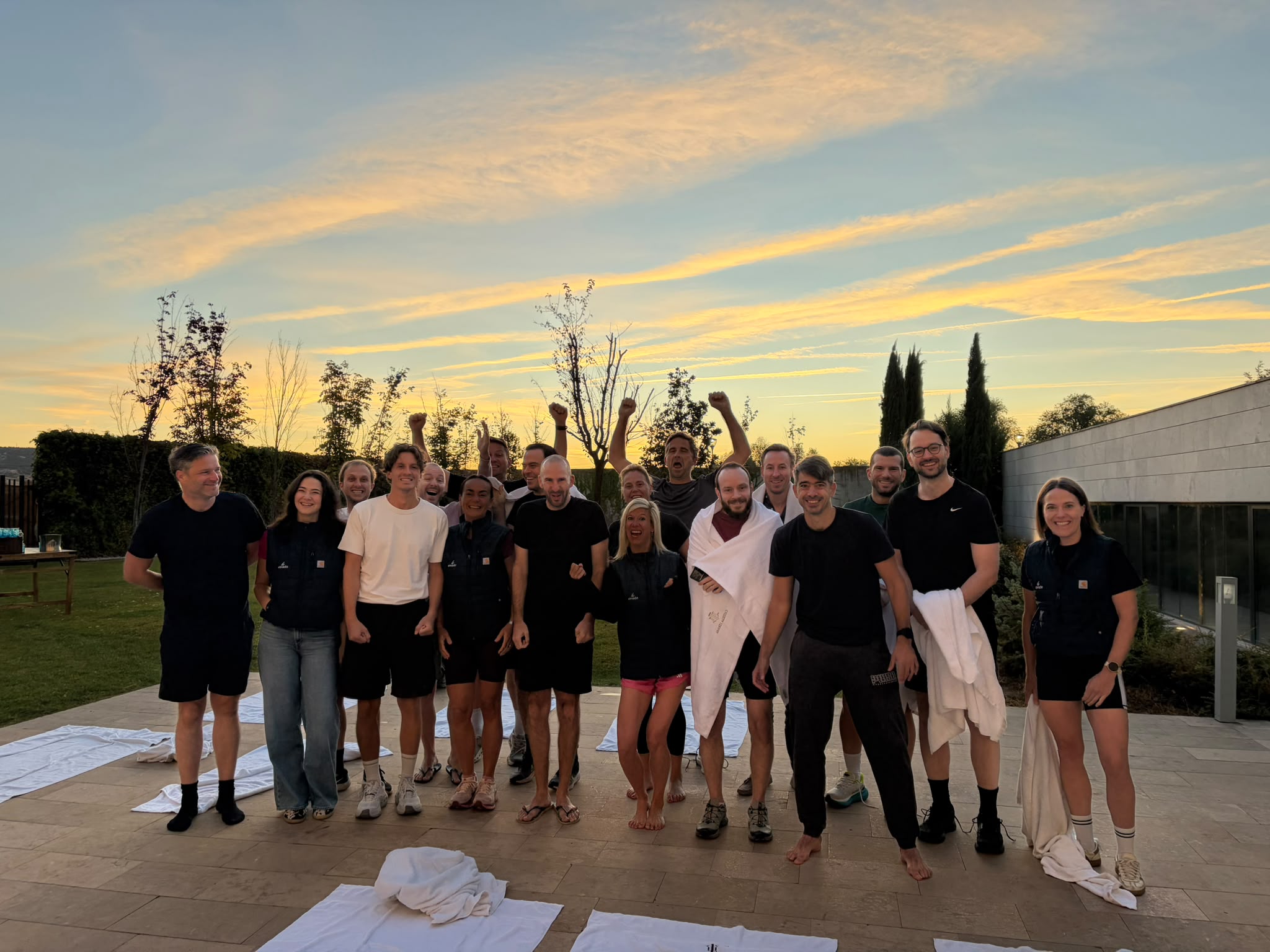 Group of Strada Partners team members outdoors at sunset, cheering after a session